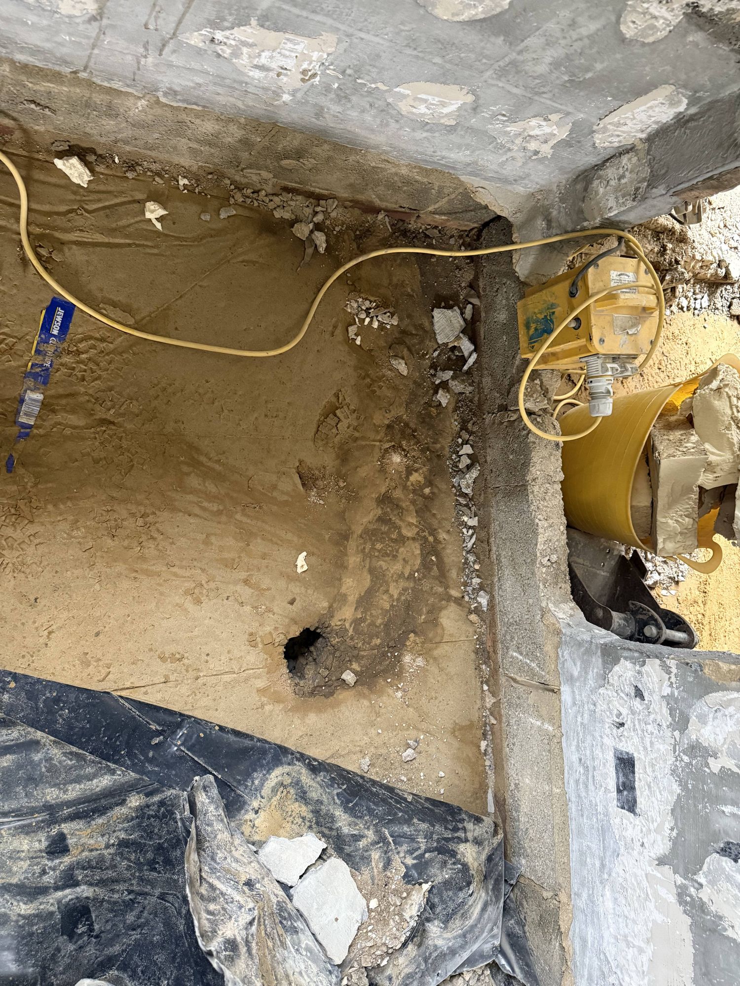 The point of entry — where the culvert forced water up through the original concrete slab. When the DPM was cut during the first rebuild, water pushed through this void and flooded the entire ground floor