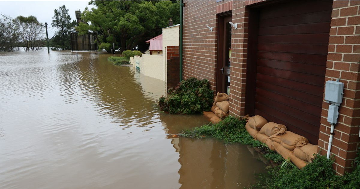 Floodwater against a brick house with sandbags at the door