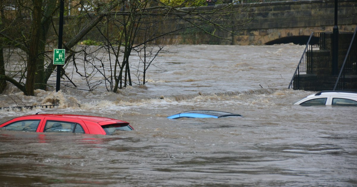 River in flood over a town street with cars submerged