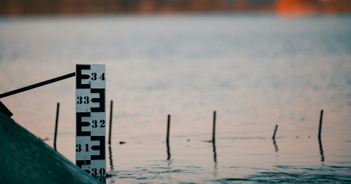 River depth gauge post standing in water